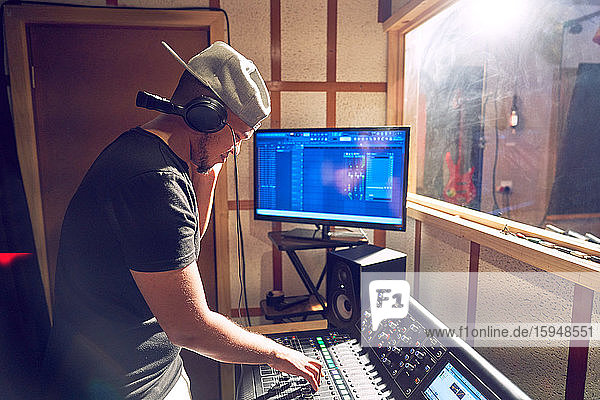 Männlicher Musikproduzent  der am Soundboard im Tonstudio arbeitet