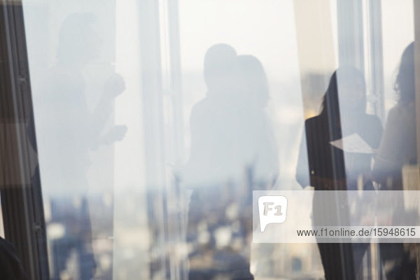Silhouette von Geschäftsleuten  die im Bürofenster sprechen