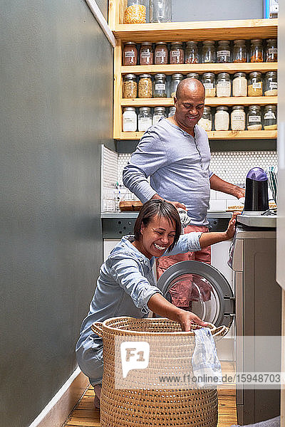 Glückliches Paar beim Wäschewaschen in der Küche
