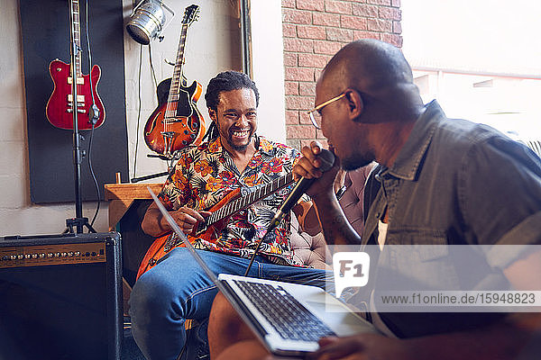 Happy male musicians practicing in recording studio