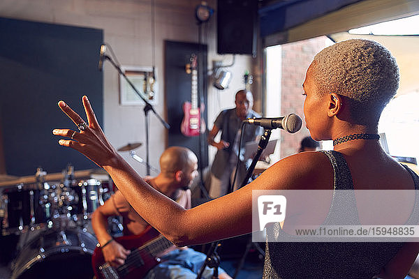 Female musician singing into microphone in garage recording studio