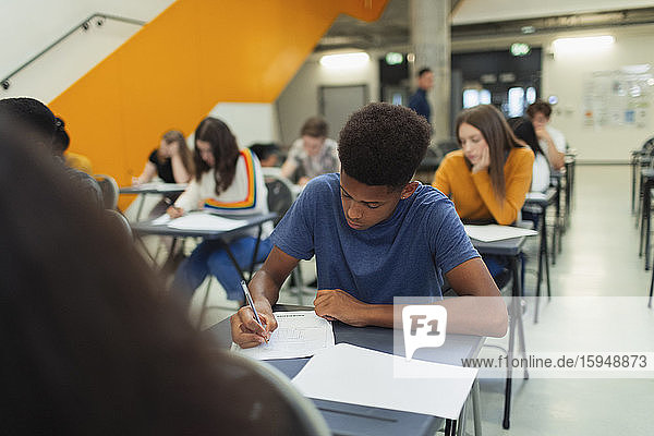 Focused high school boy student taking exam at desk