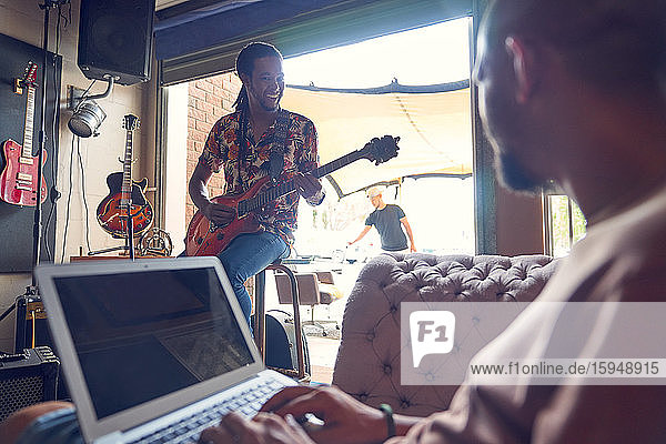 Musicians with laptop and electric guitar in recording studio
