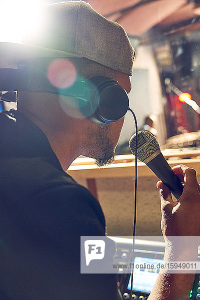 Männlicher Musikproduzent mit Mikrofon im Aufnahmestudio