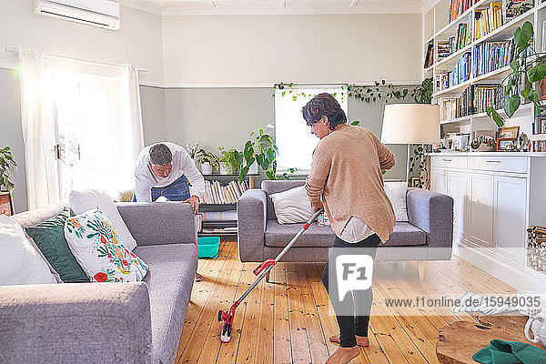Mature couple mopping and cleaning living room