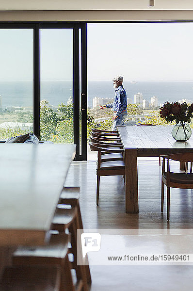 Mann steht auf sonniger  moderner Terrasse mit Meerblick