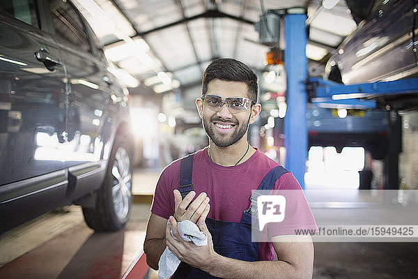 Porträt eines selbstbewussten Mechanikers beim Händewischen in einer Autowerkstatt