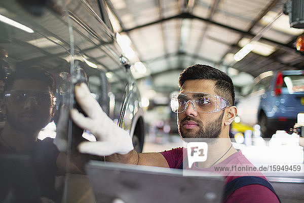 Fokussierter männlicher Mechaniker mit digitalem Tablett in Autowerkstatt