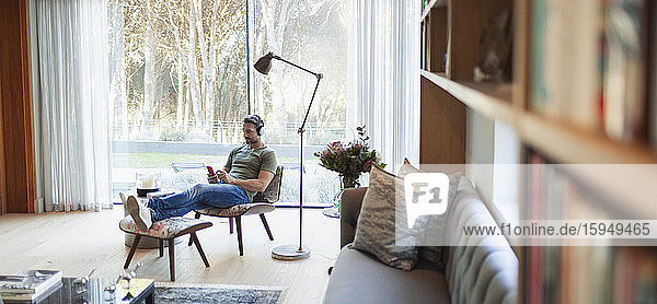 Man relaxing  listening to music with headphones and mp3 player in living room