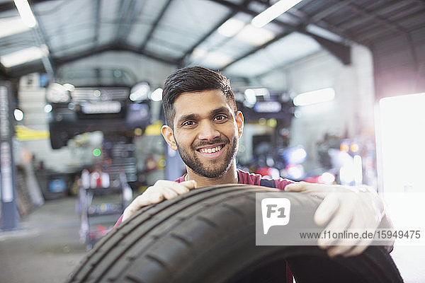 Porträt eines selbstbewussten Mechanikers mit Reifen in einer Autowerkstatt