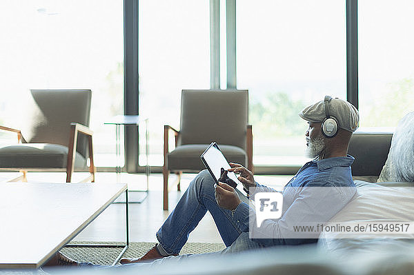Man relaxing  listening to music with headphones and digital tablet in living room