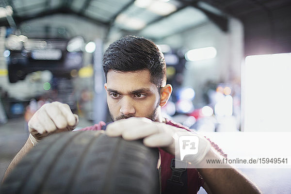 Fokussierter männlicher Mechaniker untersucht Reifen in Autowerkstatt