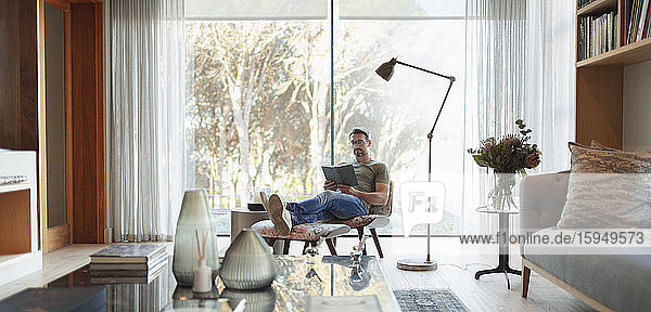 Mann entspannt sich  liest mit erhobenen Füßen im Wohnzimmer