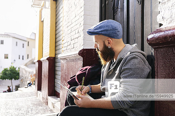 Mann sitzt an der Eingangstür in der Stadt und zeichnet eine Skizze  Granada  Spanien