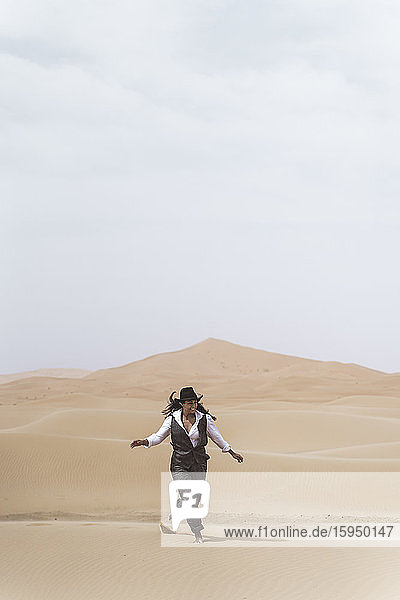 Modische junge Frau tanzt barfuss auf einer Sanddüne  Merzouga-Wüste  Marokko