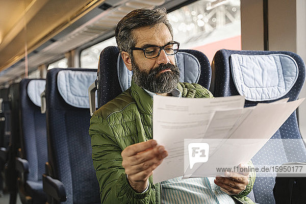 Man sitting in train reading documents