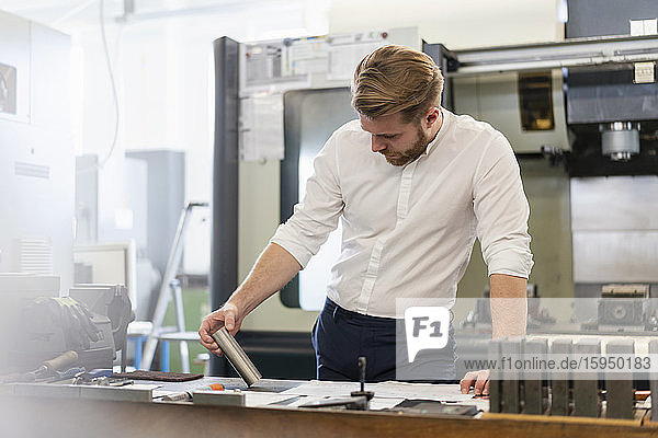 Man looking at plan and workpiece in a factory
