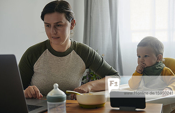 Mutter und kleiner Sohn schauen gemeinsam am Laptop zu Hause