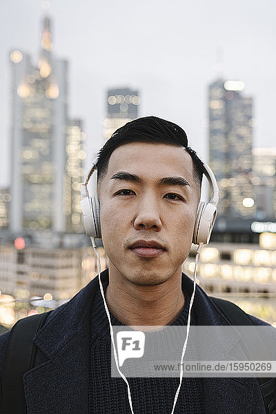Porträt eines Mannes mit Kopfhörern vor der Stadtsilhouette  Frankfurt  Deutschland