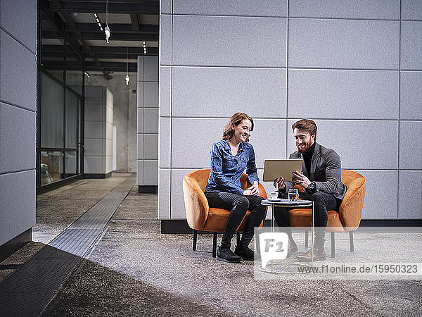 Geschäftsmann mit Tablett und Geschäftsfrau bei einer Besprechung im modernen Büro