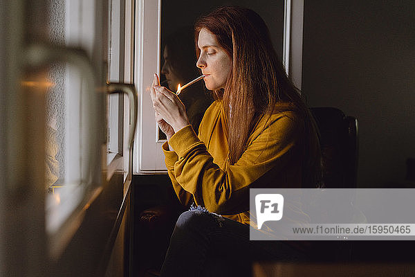 Rothaarige Frau sitzt am offenen Fenster Beleuchtungsstelle