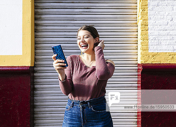 Happy woman using smartphone at a building in the city