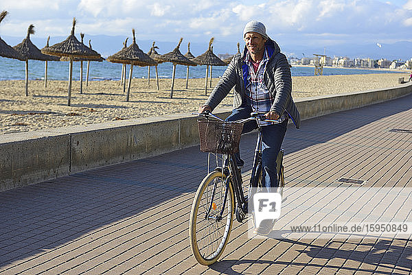Mann fährt im Winter mit dem Fahrrad an der Strandpromenade