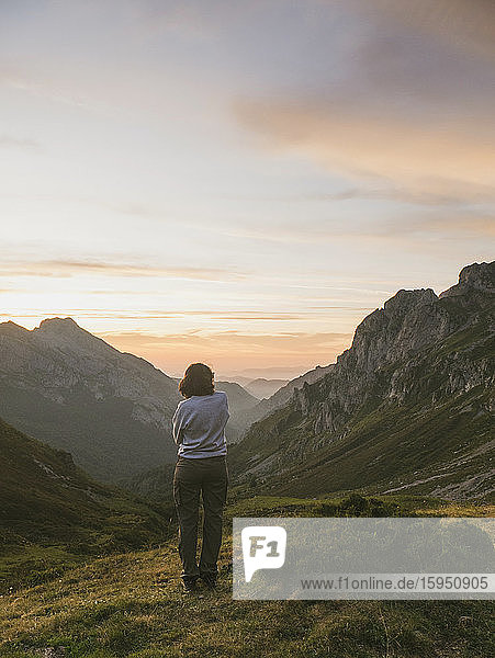 Spanien  Kantabrien  Junge Frau bewundert das Tal in den Picos de Europa im stimmungsvollen Morgengrauen