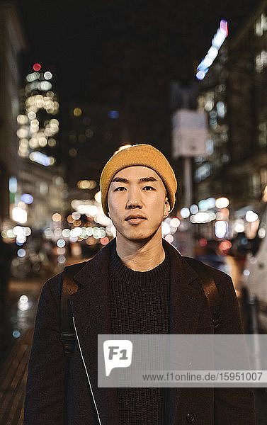 Portrait of stylish man with yellow hat in the city at night