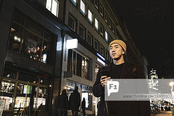Man using smartphone in the city at night