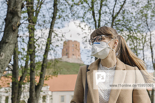 Frau mit FFP2-Maske  die in der Stadt seitwärts blickt