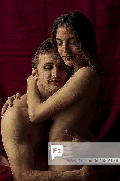 Intimes junges Paar umarmt sich vor einem Rubinvorhang