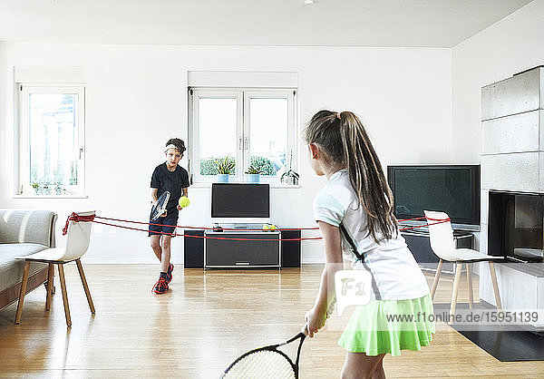 Happy siblings playing tennis at home during quarantine