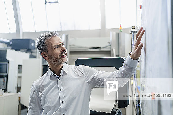 Businessman looking at plan in a factory