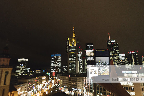 Deutschland  Hessen  Frankfurt  Hände einer Frau  die nachts per Smartphone Fotos von der Innenstadt macht