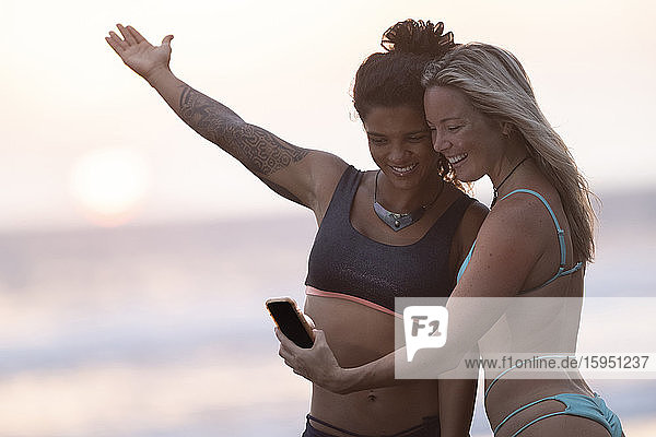 Two happy women taking selfie on the beach at sunset  Costa Rica