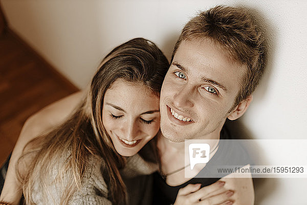 Glückliches junges Paar sitzt zu Hause auf dem Boden