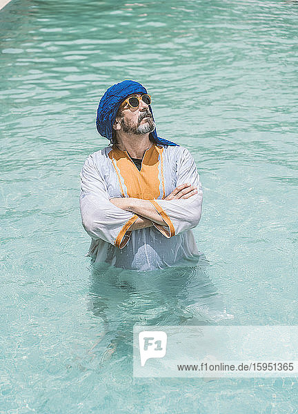 Mann mit blauem Turban  steht mit verschränkten Armen im Schwimmbad