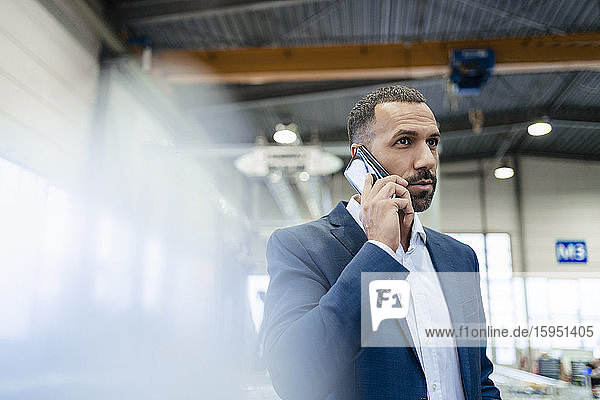 Porträt eines Geschäftsmannes in einer Fabrik am Telefon