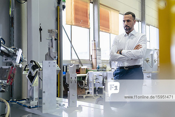 Businessman looking at modern machine in a factory