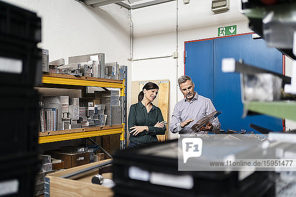Geschäftsmann und Geschäftsfrau bei einer Arbeitsbesprechung an einer Maschine in einer Fabrik
