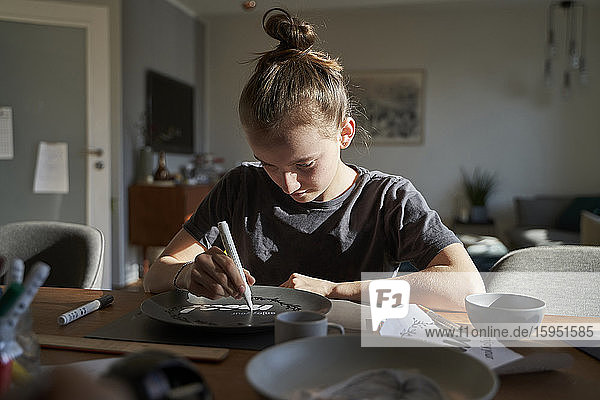 Mädchen zu Hause malt Teller mit Porzellanfarbe