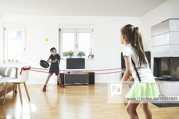 Geschwister genießen Tennis zu Hause während einer Pandemie-Situation