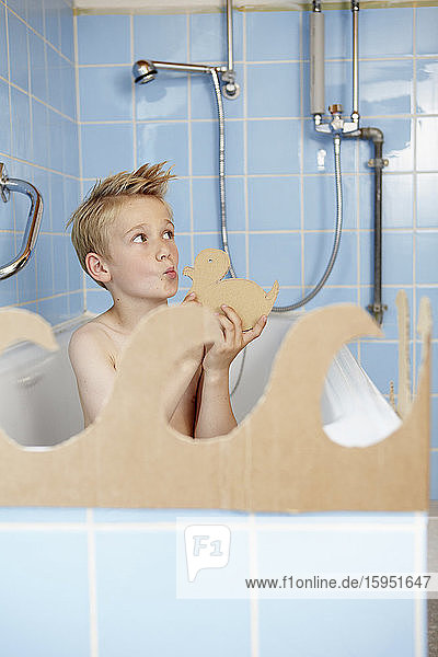 Junge spielt mit Pappgummi-Ente in der Badewanne