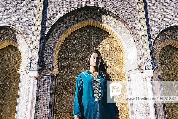 Junge Frau steht in marokkanischer Robe vor traditionellen Archiven  Marokko