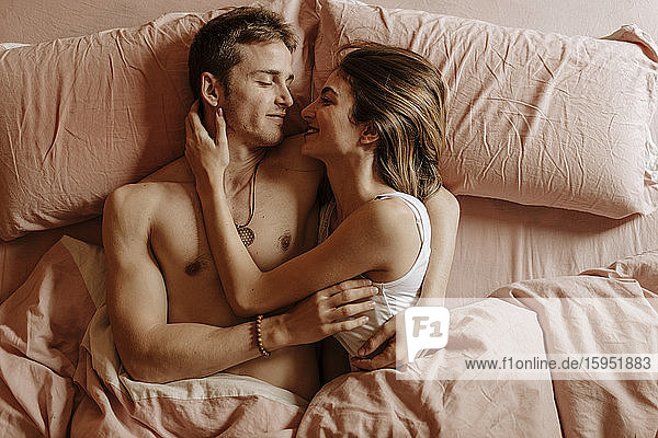 Glückliches junges Paar liegt im Bett