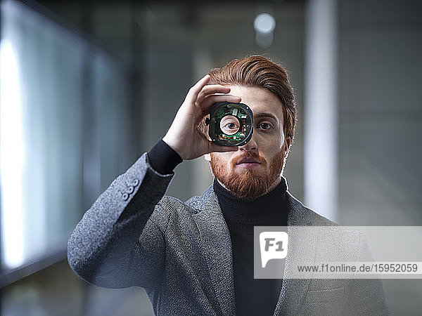 Portrait of businessman looking through an object in modern office