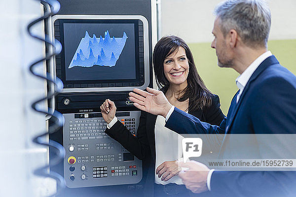Geschäftsmann und Geschäftsfrau bei einer Arbeitsbesprechung an einem Bildschirm in einer Fabrik