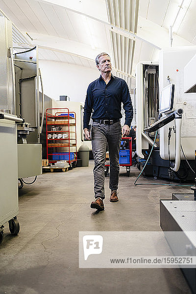 Mature man walking through production floor of factory