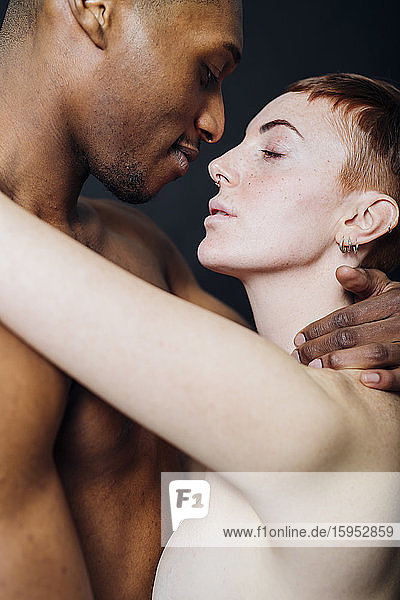 Studioporträt eines liebevollen  nackten  gemischtrassigen Paares  das sich umarmt